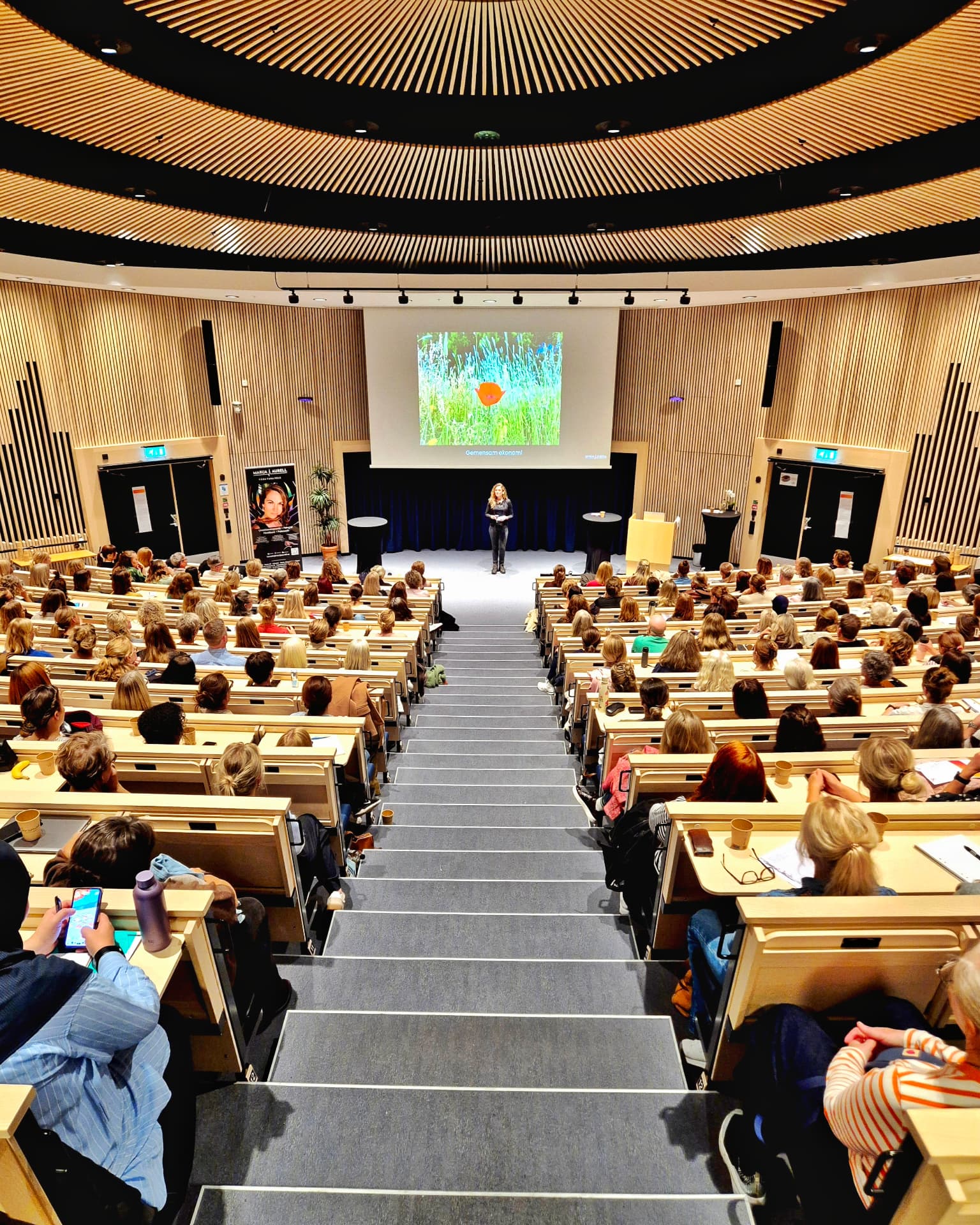 Marija Aurell föreläser på scen i ett fullsatt auditorium